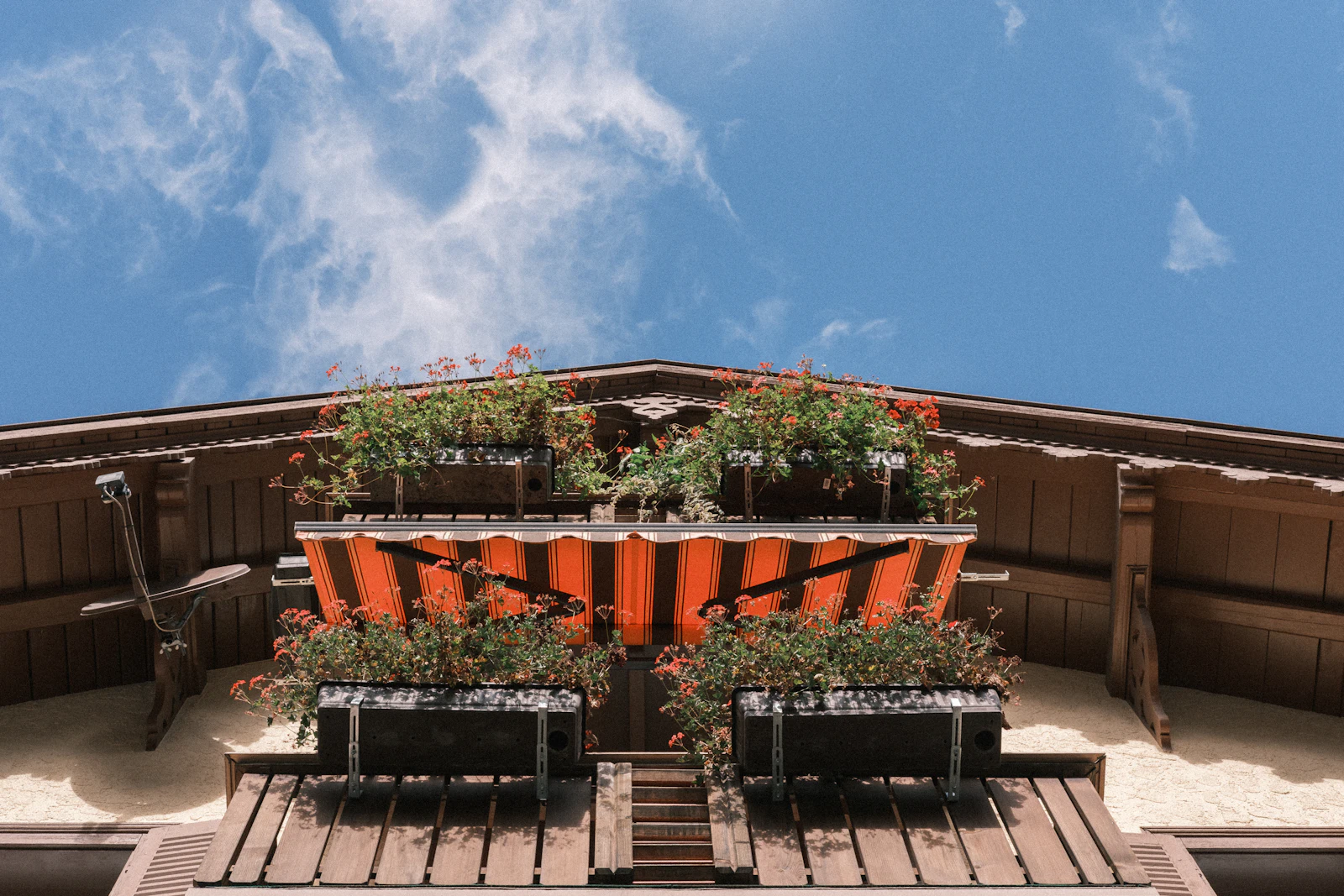 Balkon mit Blumen und orangefarbener Markise